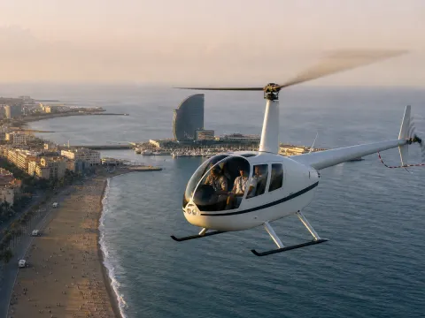 Robinson R44 helicopter banking over the Barcelona shoreline