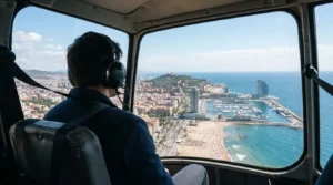 Solo passenger in a headset looking out of a helicopter window at Barceloneta beach, Port Vell marina and the sea