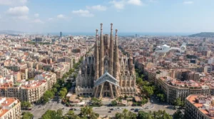 Aerial view of the Sagrada Familia towers above the Eixample street grid, with a small helicopter flying at a distance