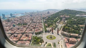 Aerial view of the wooded Montjuic hill above Placa Espanya and Barcelona's street grid in midday light